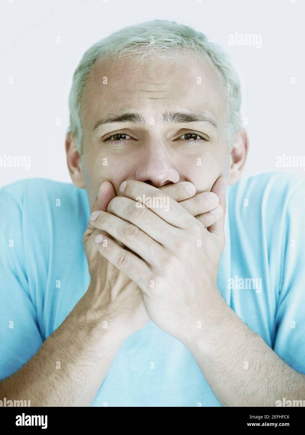 Portrait of a young man covering his mouth with his hands Stock Photo ...