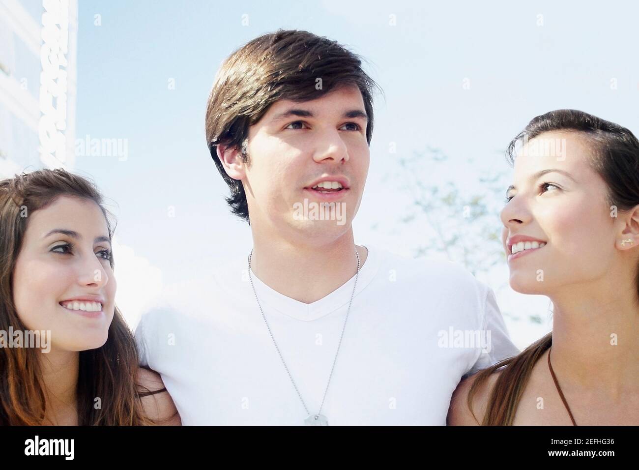 Close up of a young man and two young women smiling Stock Photo - Alamy