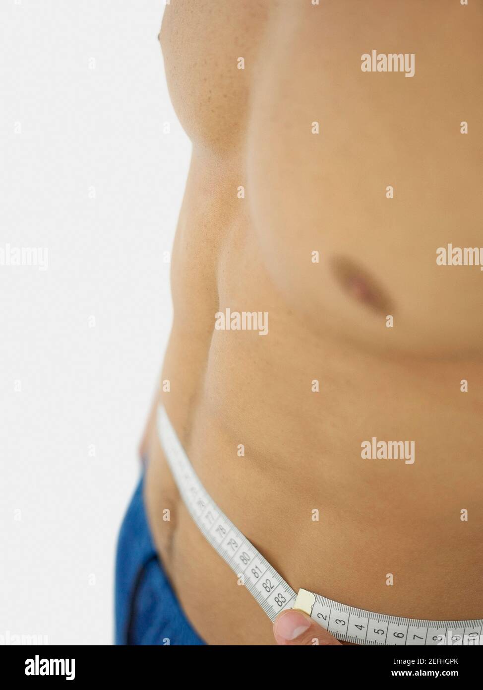 Close up of a person measuring his waist with a tape measure Stock Photo