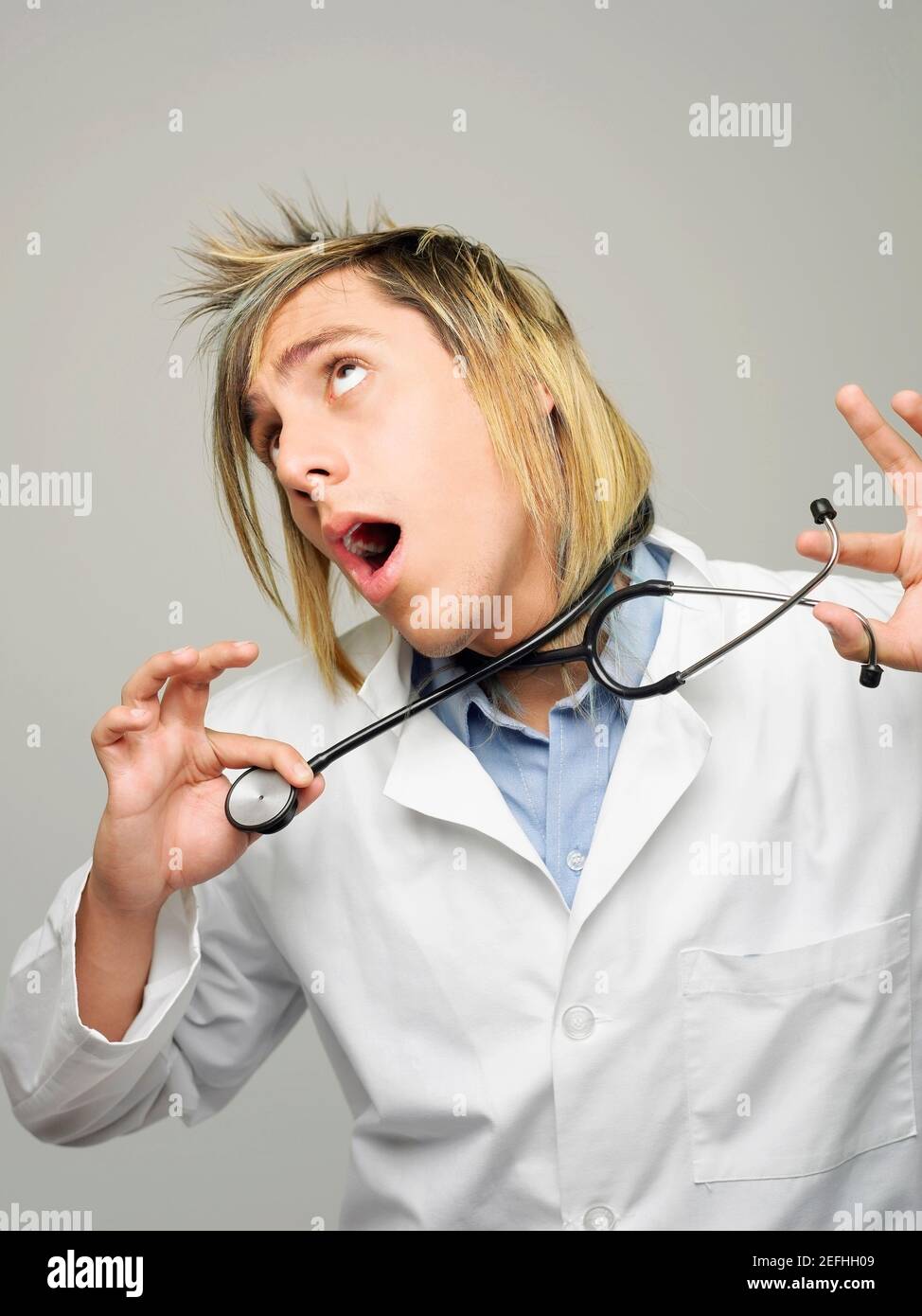 Close up of a male doctor strangling himself with a stethoscope Stock Photo