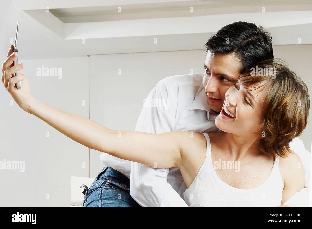 Young woman taking a picture with a mid adult man embracing her from ...
