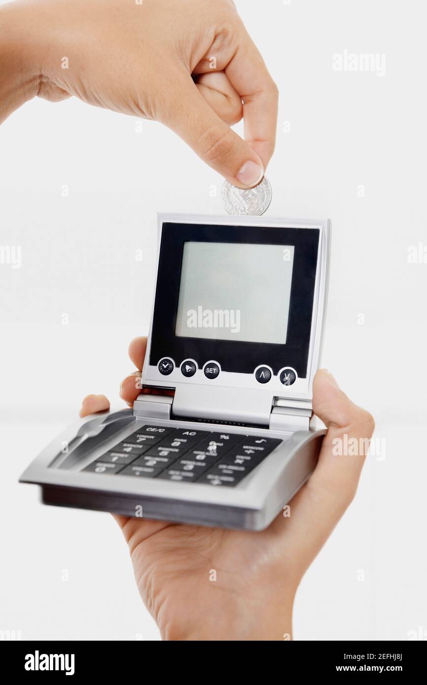 Close up of a personŽs hand inserting a coin into a calculator Stock Photo