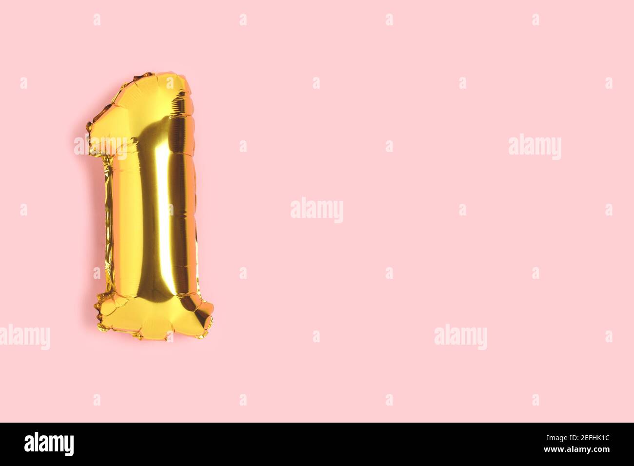 Number 1 golden balloon with copyspace. One year anniversary celebration concept on a pink background. Stock Photo