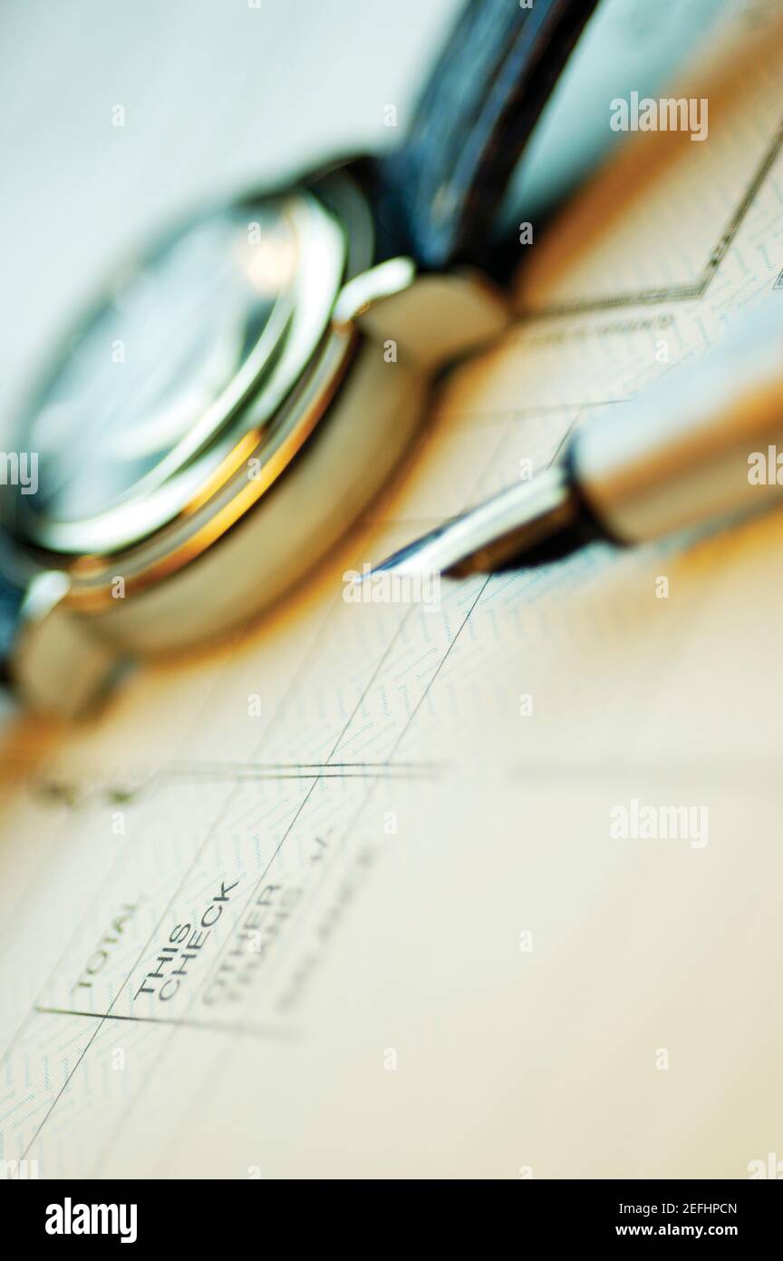 Close-up of a fountain pen and a wristwatch on a bank deposit slip Stock Photo