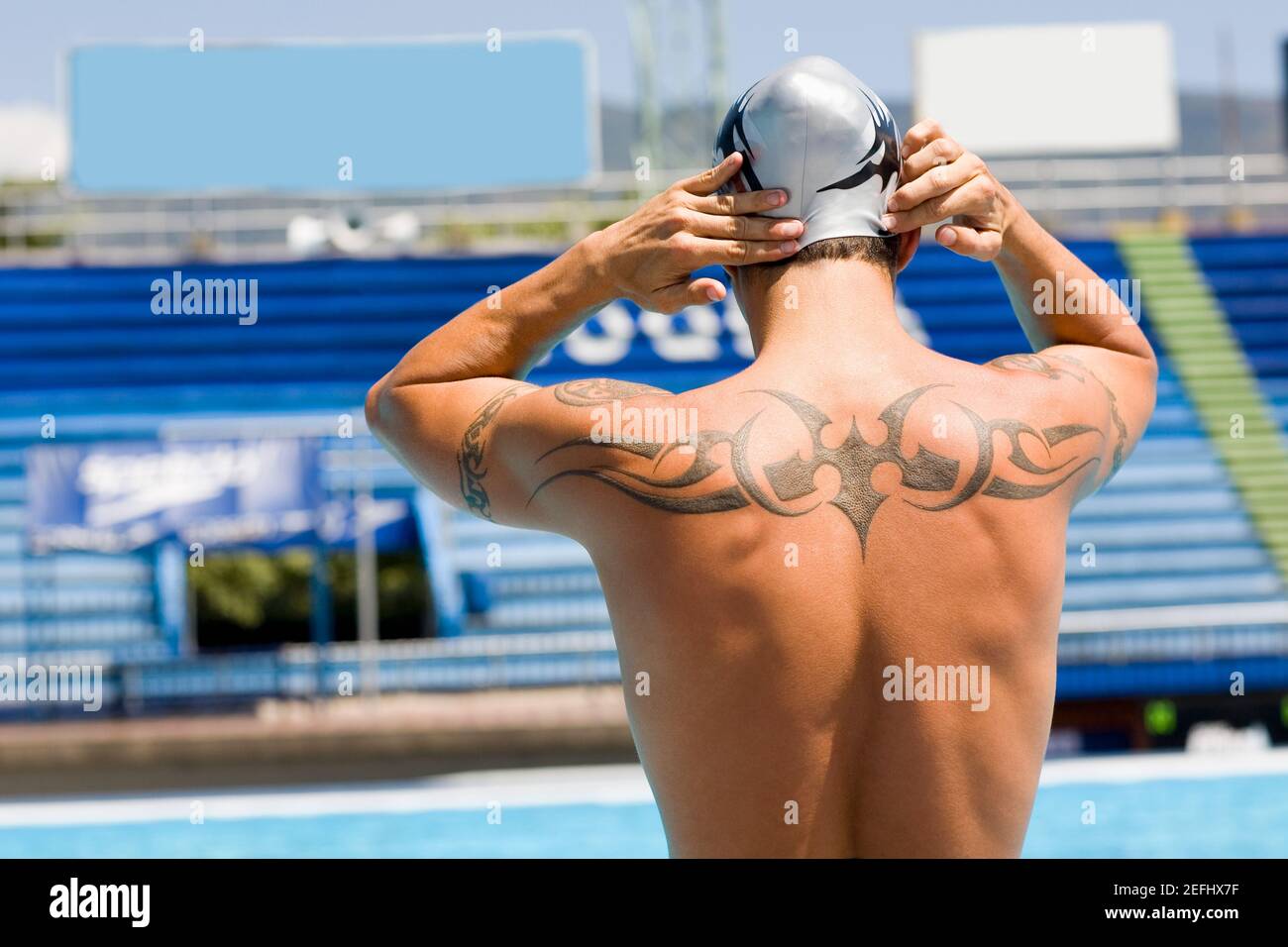 Rear view of a man with a tattoo on his back at the poolside Stock Photo -  Alamy