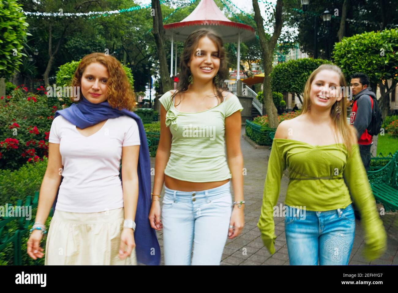 Three young women walking on a walkway in a park Stock Photo - Alamy