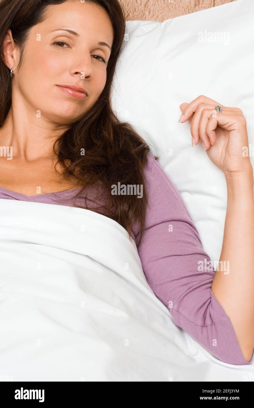 Portrait of a mid adult woman lying on the bed Stock Photo - Alamy