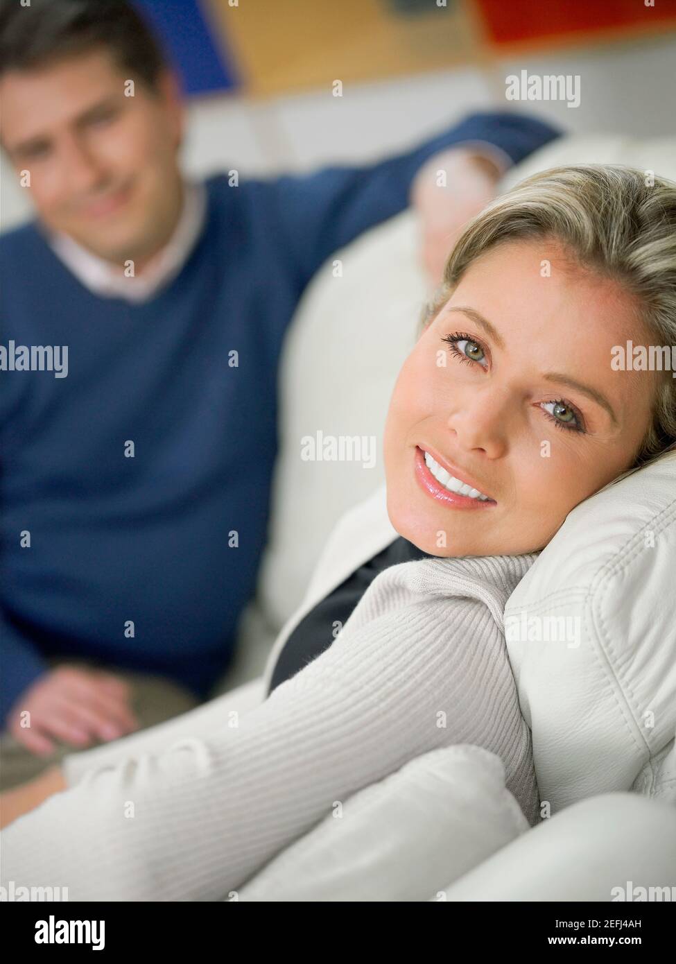 Portrait of a mid adult woman sitting on a couch and smiling and a ...