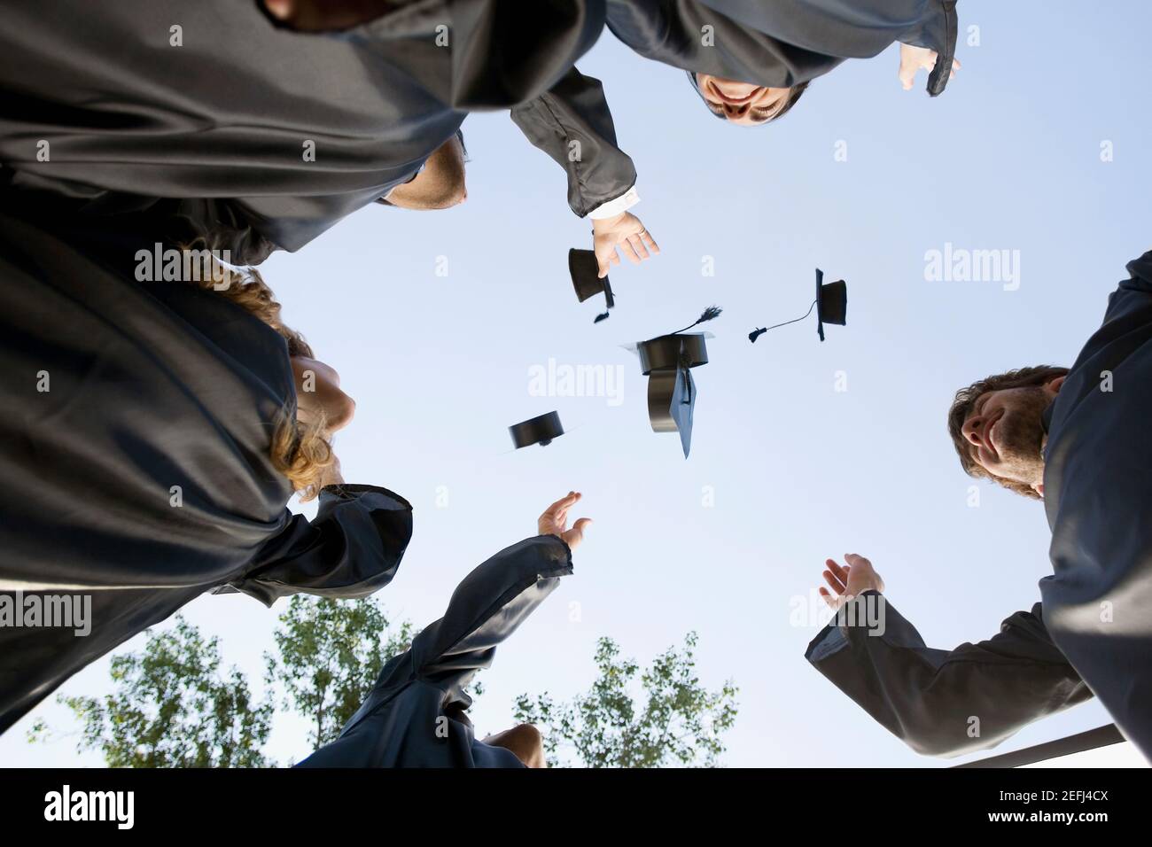 Low angle view of graduate students throwing their mortar boards in air Stock Photo