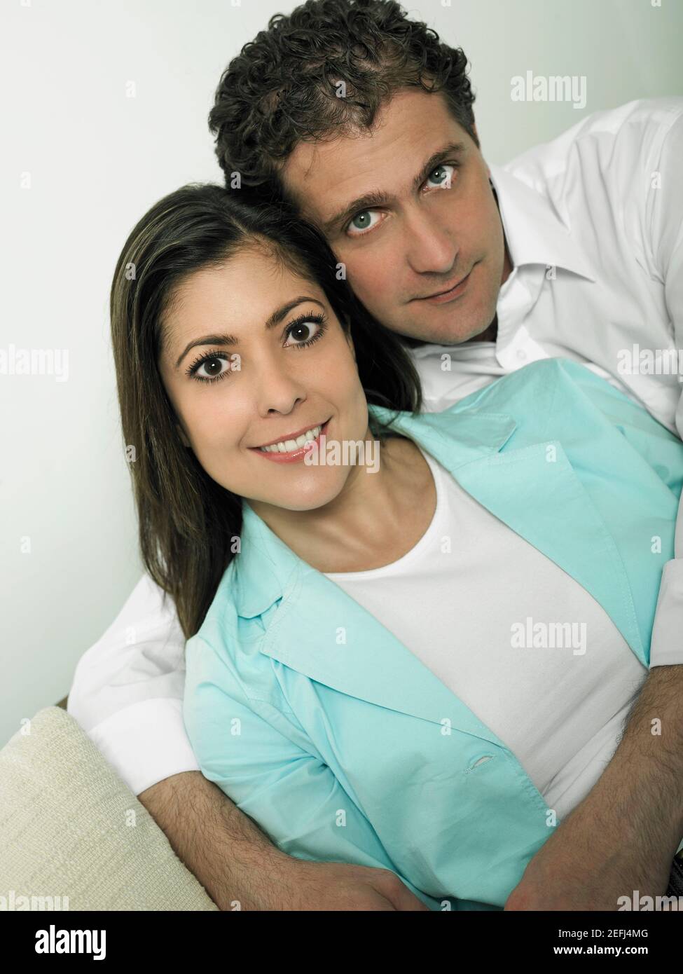 Portrait of a mid adult man embracing a mid adult woman form behind ...