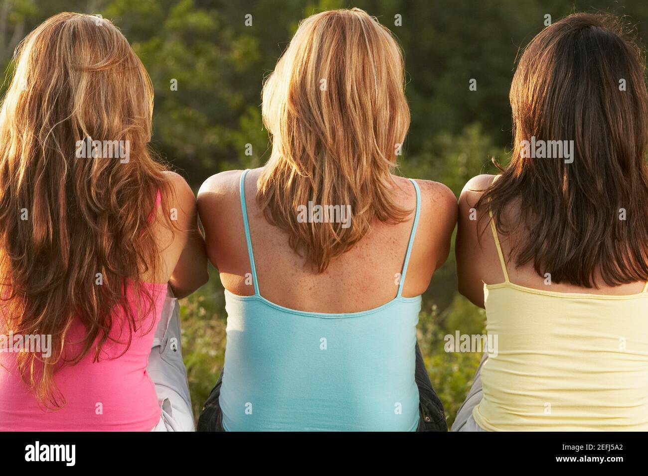 Rear view of three women sitting side by side Stock Photo