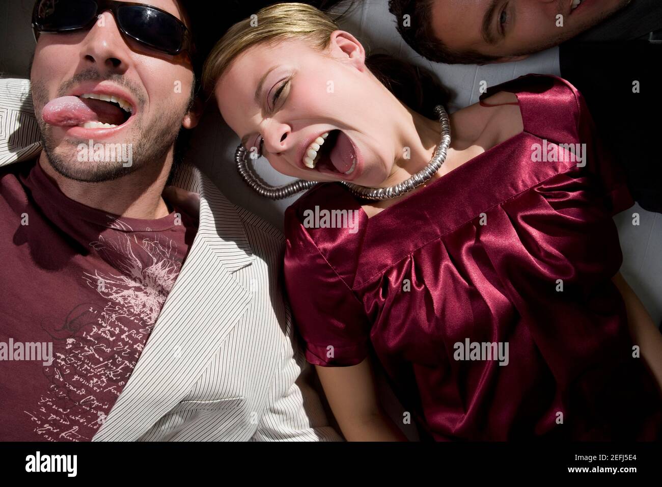 High angle view of a young woman lying down with a young man sticking his tongue out Stock Photo
