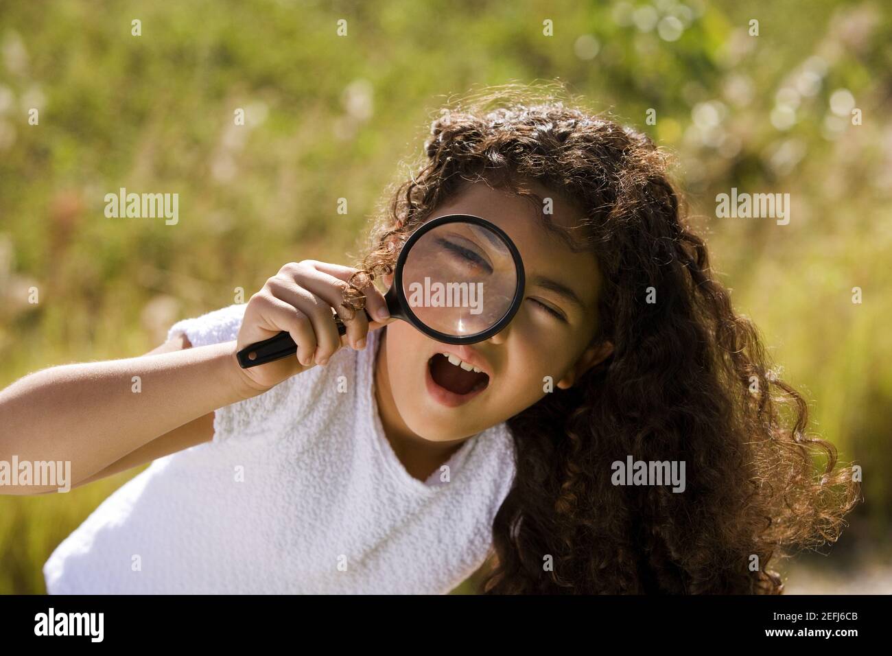 Portrait of a girl looking through a magnifying glass Stock Photo - Alamy