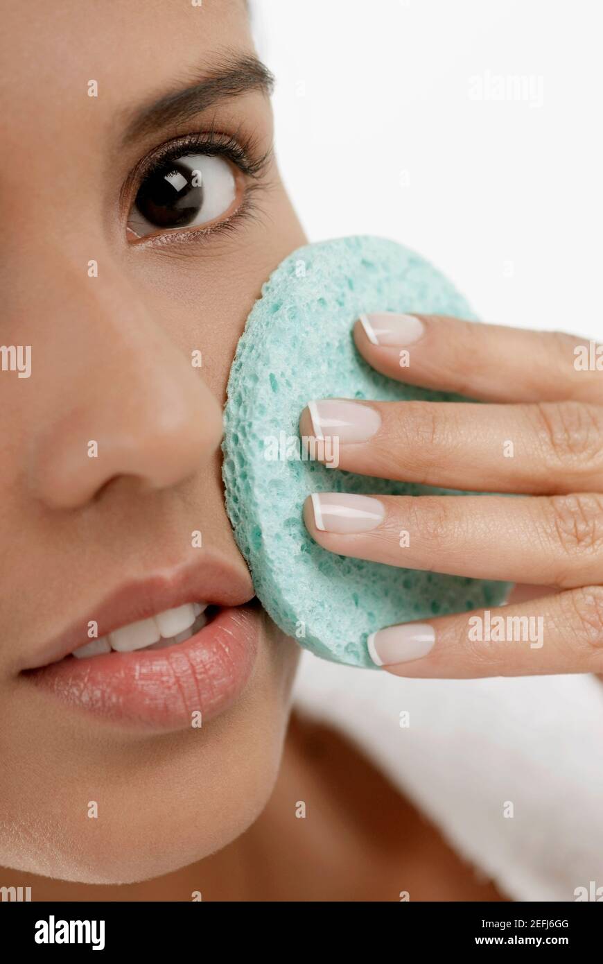 Portrait of a young woman scrubbing her face with a sponge Stock Photo