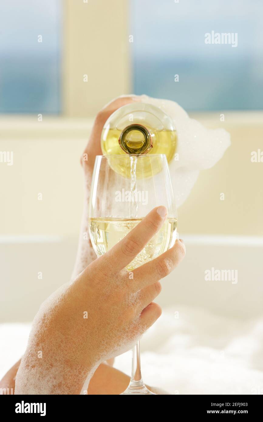 Close-up of a womanÅ½s hand pouring champagne in champagne flute Stock Photo