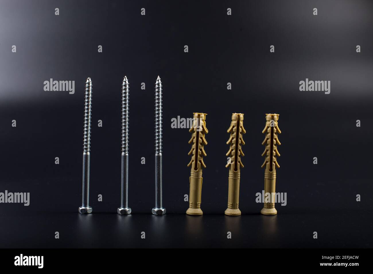 Long dowels with self-tapping screws on a black background with copyspace Stock Photo