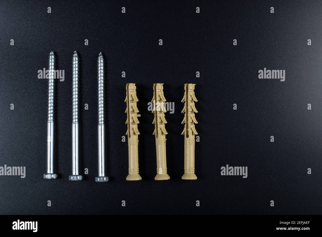 Dowels with self-tapping screw on black background with copy space. Stock Photo