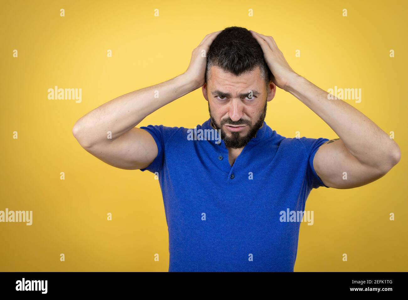 Handsome man with beard wearing blue polo shirt over yellow background ...