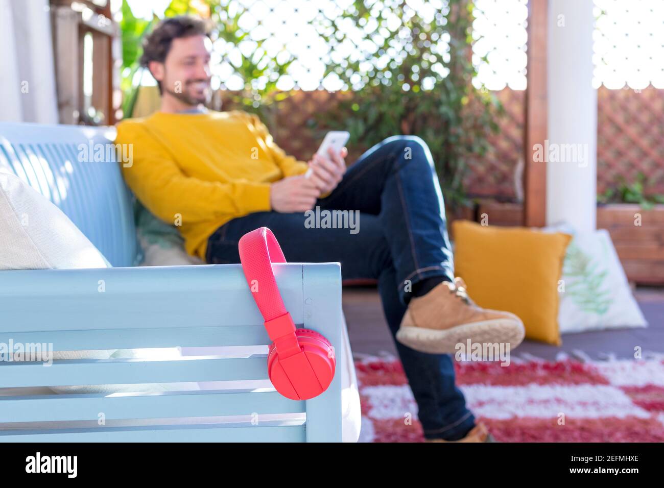 Unfocus and unrecognizable smiling man with red headphones in the foreground and a mobile phone Stock Photo