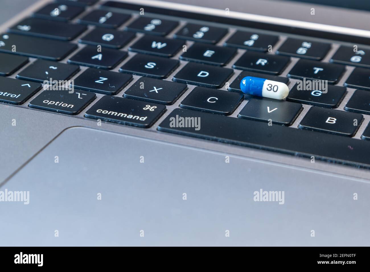 Blue and white tablet pills on a black computer keyboard. Grey