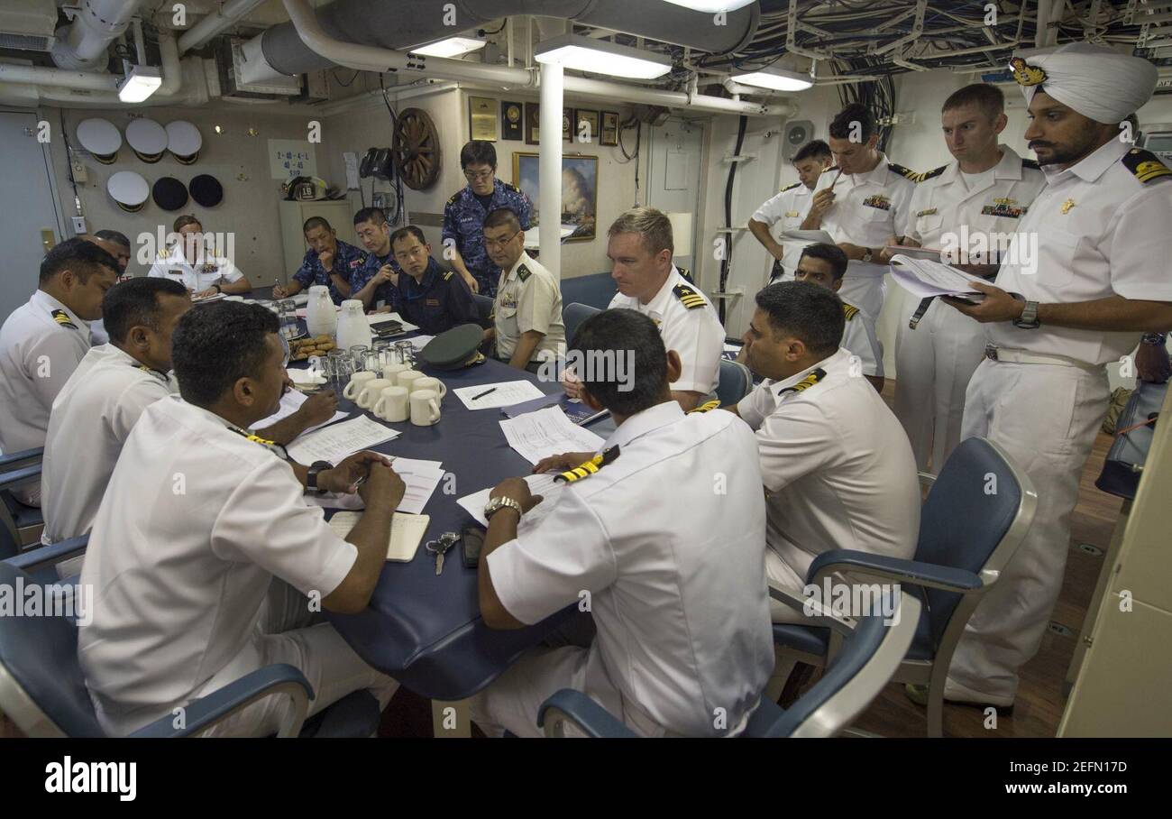 Officers from the Indian Navy, Japan Maritime Self Defense Force, and U.S. Navy meet for an executive officer's call in the wardroom of the USS Fort Worth. Stock Photo