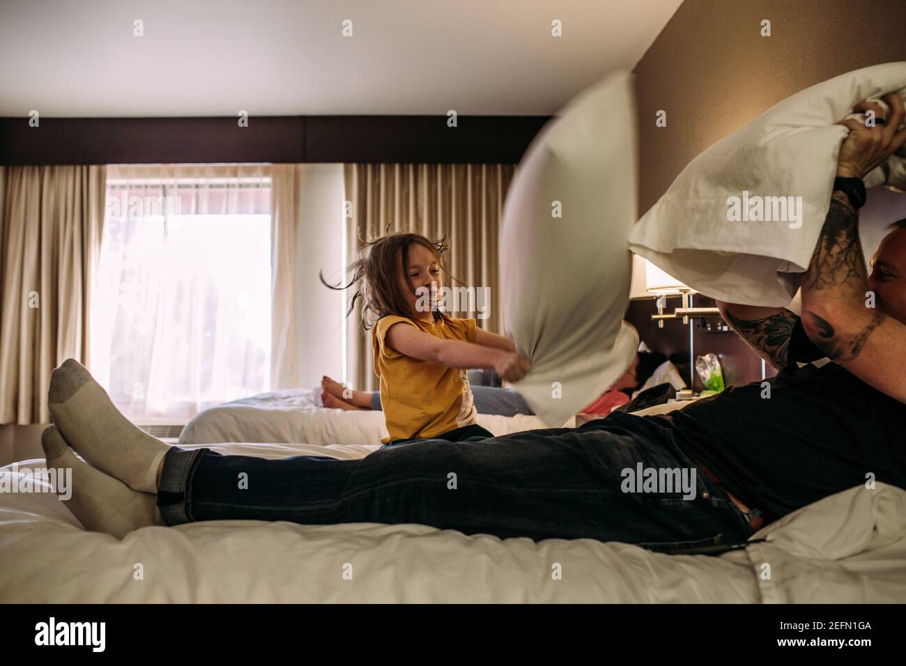 https://c8.alamy.com/comp/2EFN1GA/young-girl-and-dad-having-a-pillow-fight-in-a-hotel-room-2EFN1GA.jpg