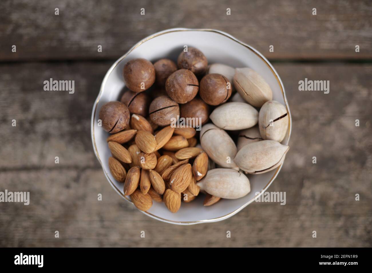 Mixed nuts in white plate on a wooden table Stock Photo