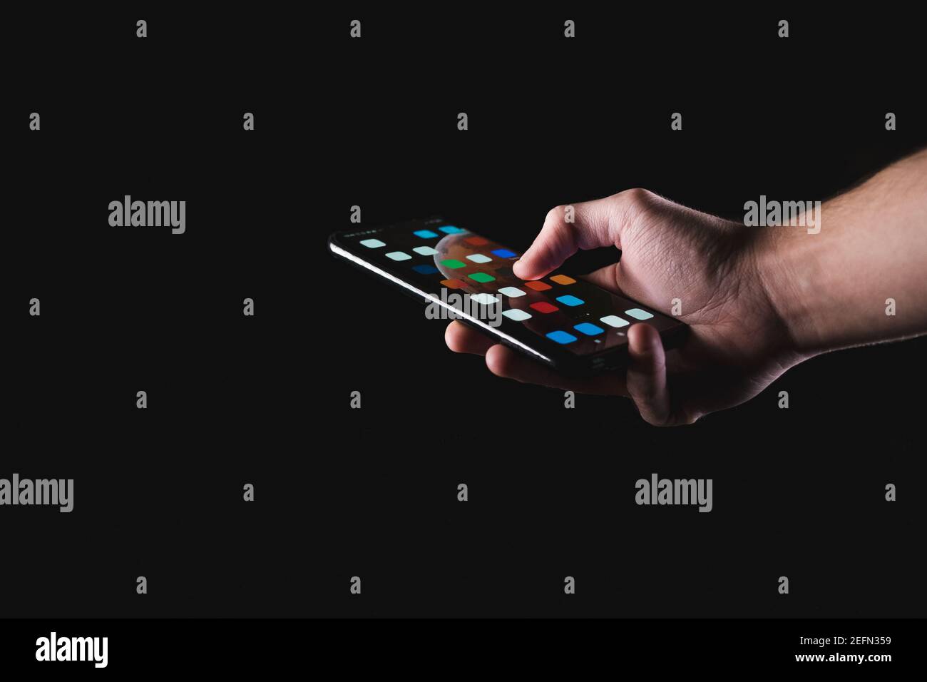 Male hand holding smartphone in black background Stock Photo
