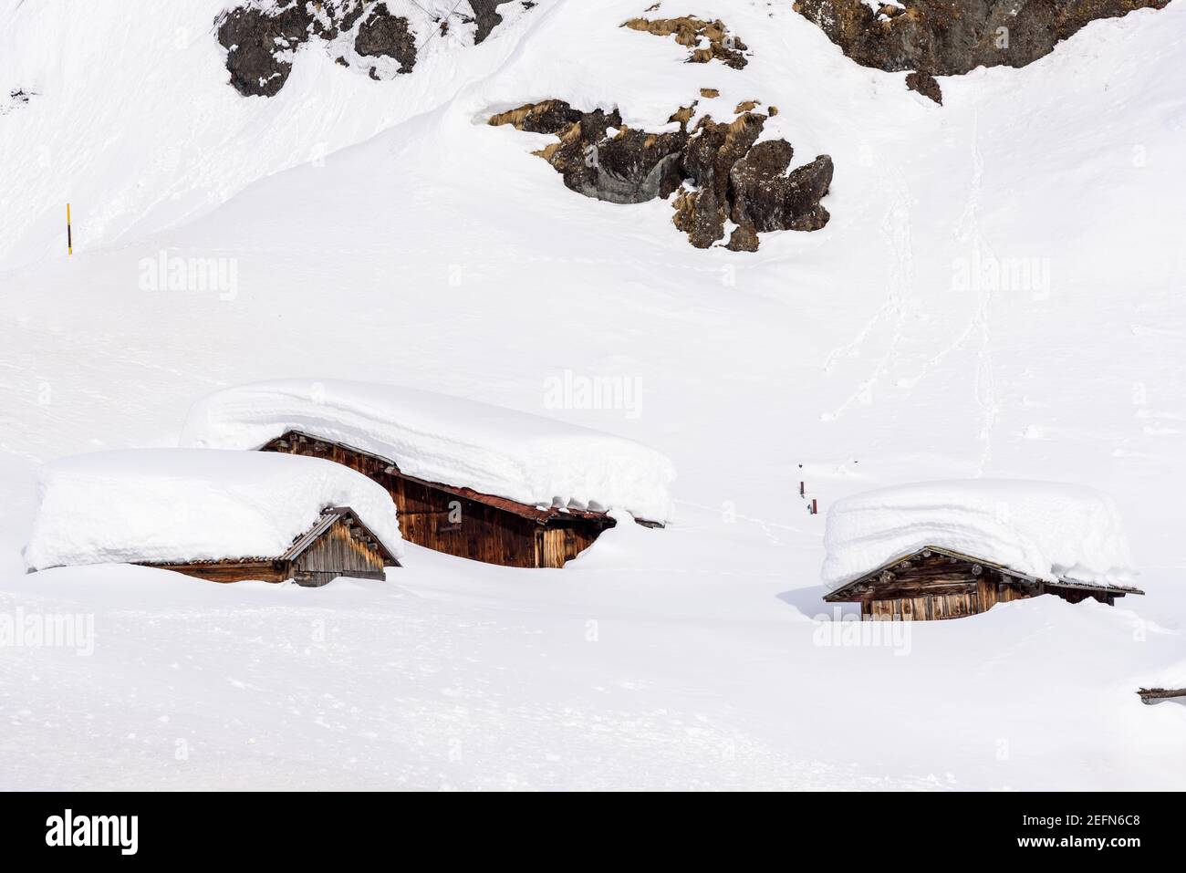 Wooden mountain huts almost completely covered in snow after a heavy snowfall in the Europeans Alps Stock Photo