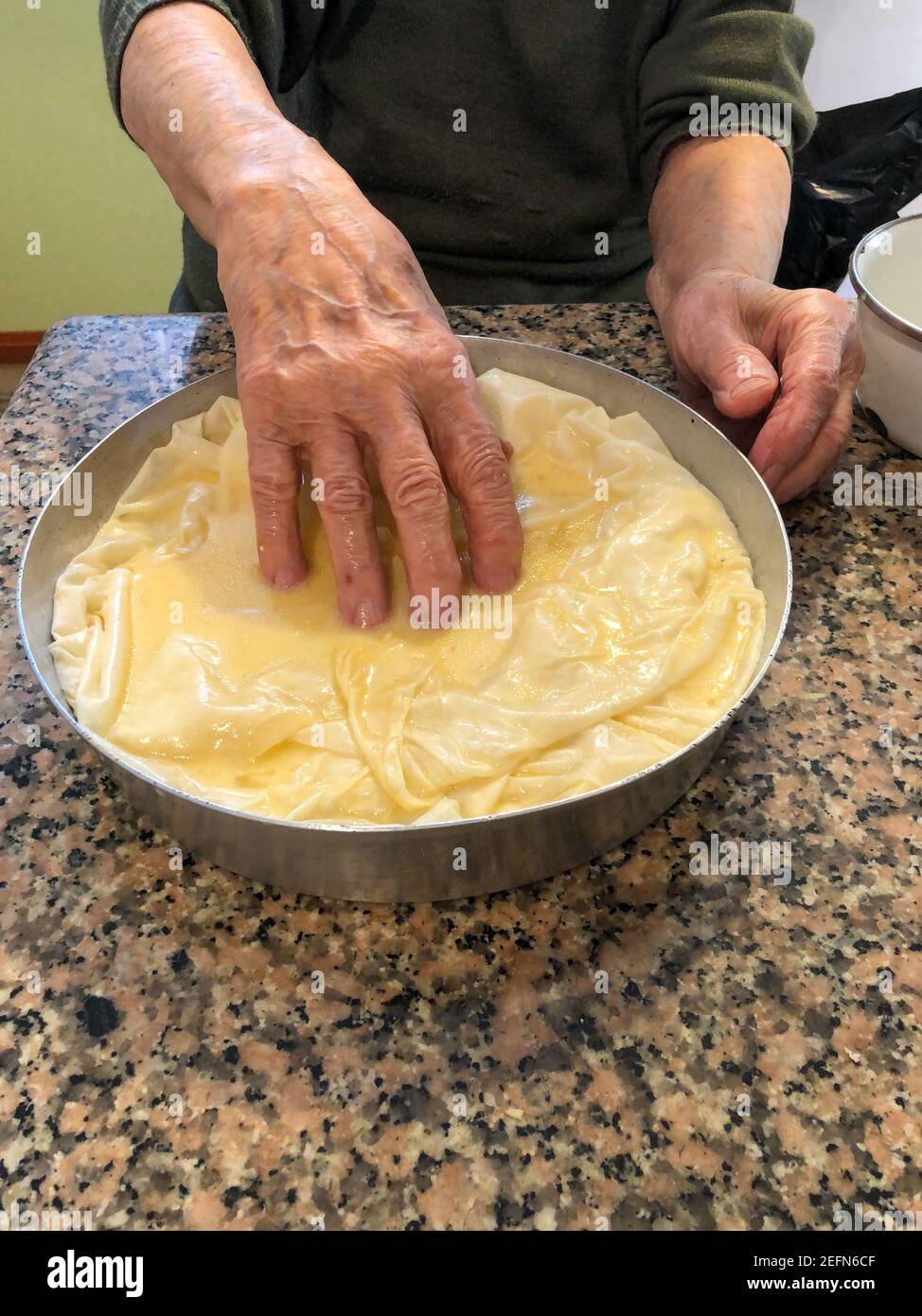 close up wrinkled hands making dough pastry in the kitchen Stock Photo