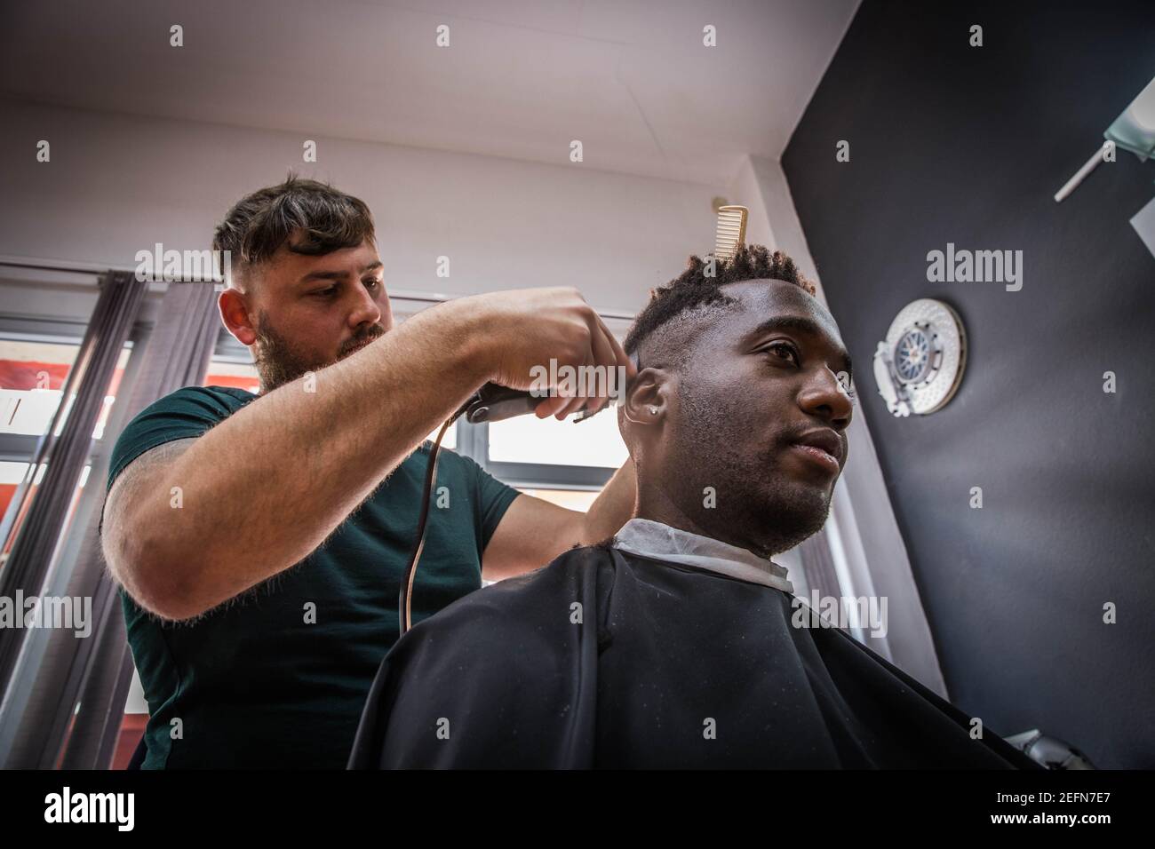 a young African boy gets his hair cut by his barber Stock Photo
