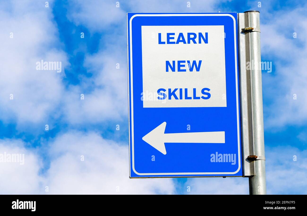 Learn new skills conceptual road sign against blue sky with clouds. Copy space. Stock Photo