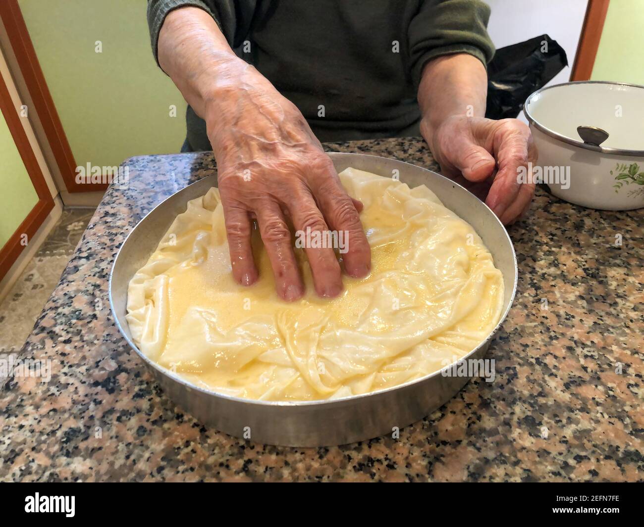 close up wrinkled hands making dough pastry in the kitchen Stock Photo