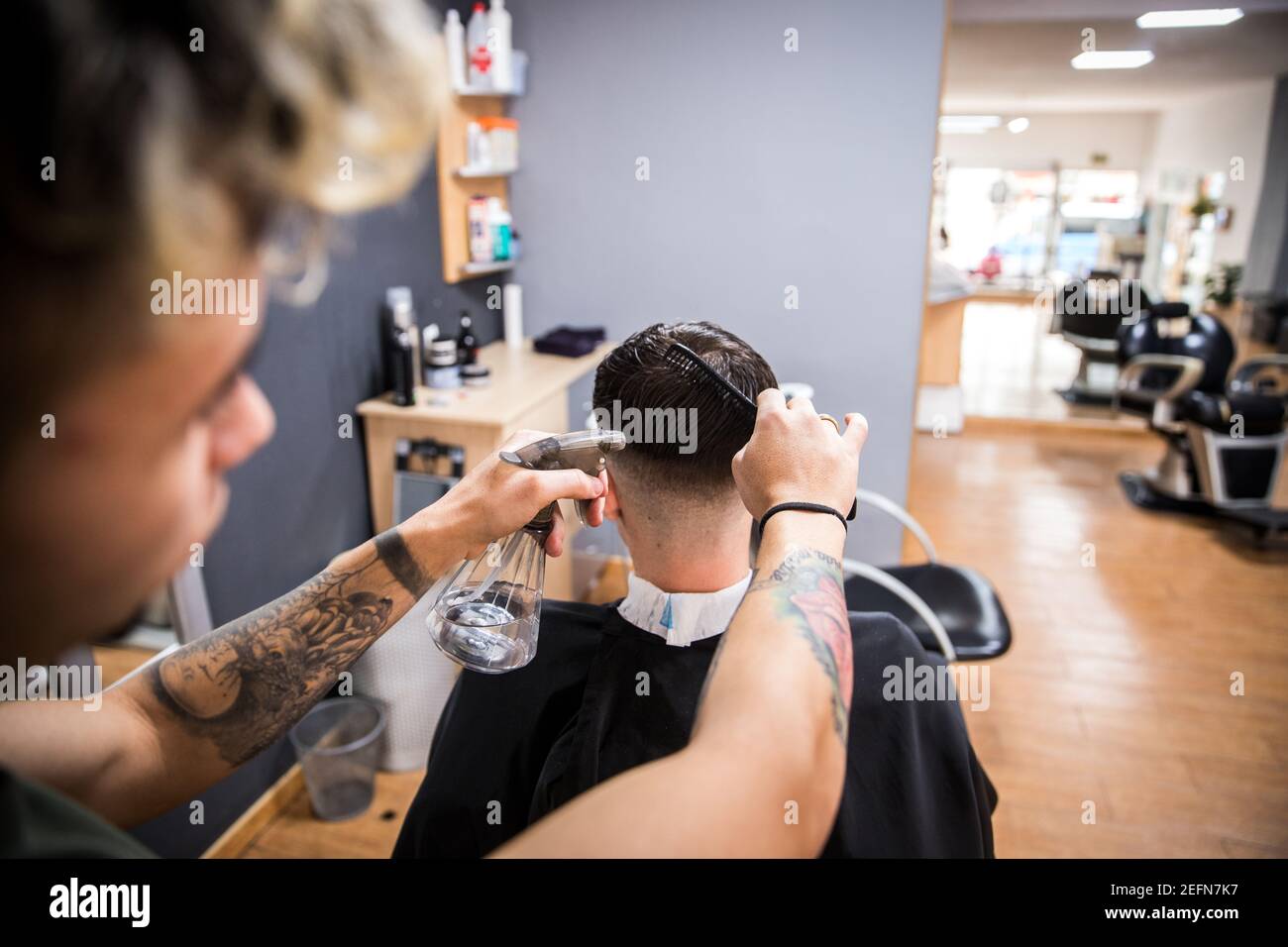 Barber wets the client's hair with a spray and then combs it. Stock Photo