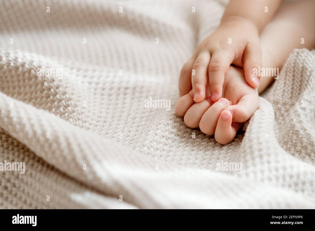 Baby hands resting on a knitted blanket Stock Photo