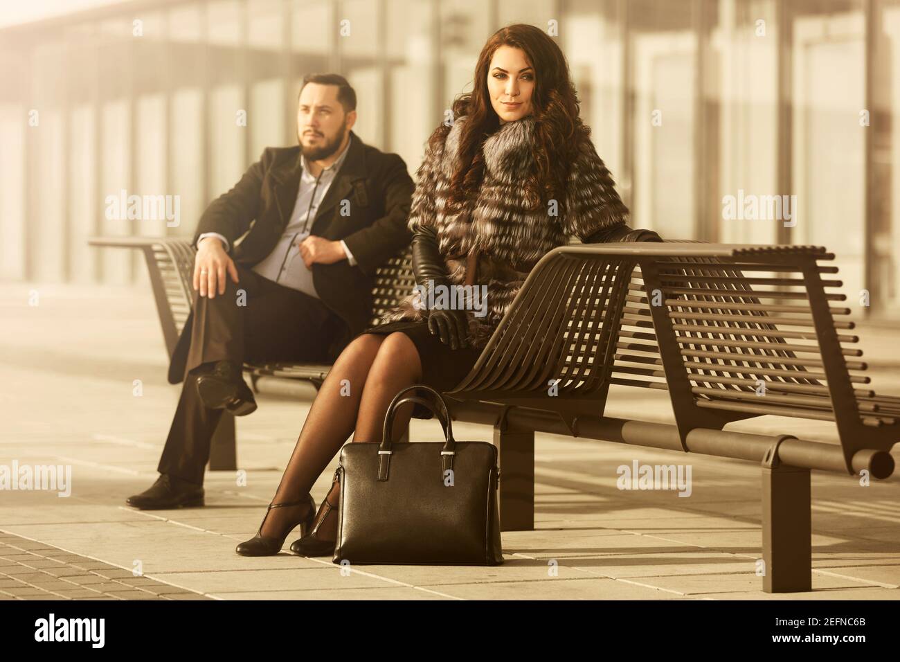 Young fashion couple in conflict on city street Stylish trendy man in classic black coat and woman in fox fur jacket Stock Photo