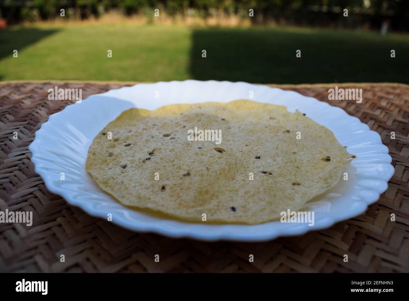 Traditional Indian papad or appal or pappadums served in white plate served outdoors. Stock Photo