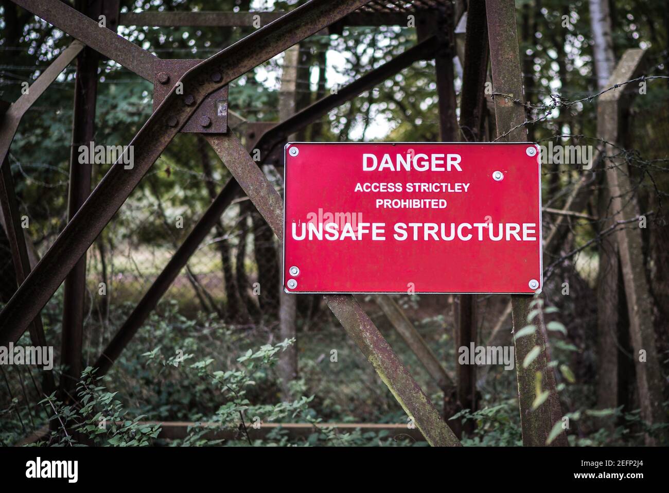 Danger Unsafe Structure sign attached to rusty old metal tower which is in a run down derelict condition keep out risk of injury Stock Photo