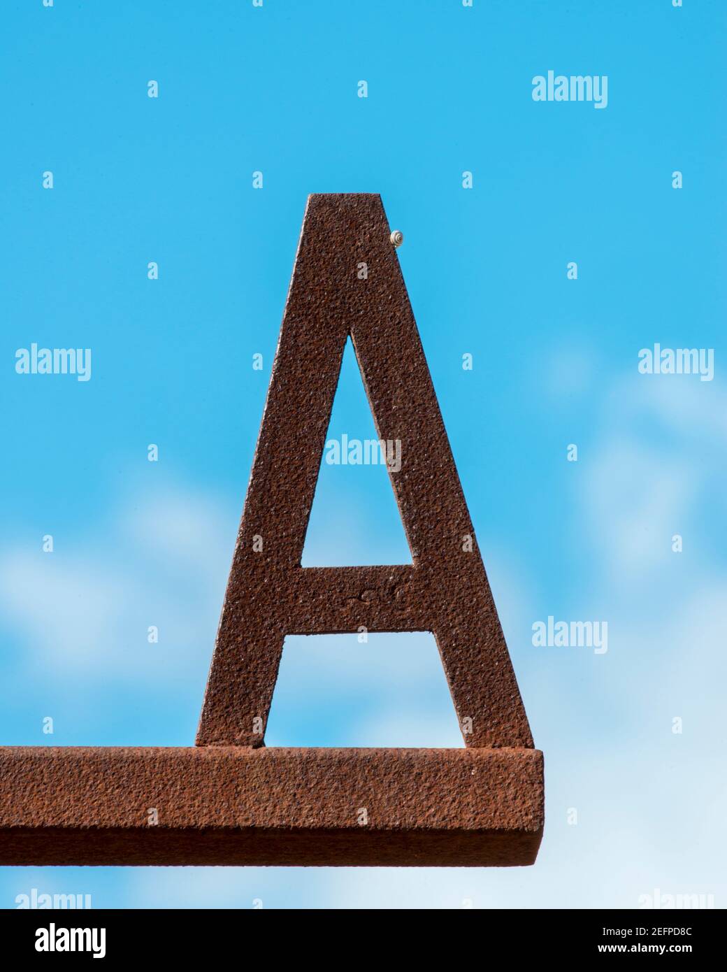 Rusty letter A with a little snail sitting on it against a blue sky Stock Photo