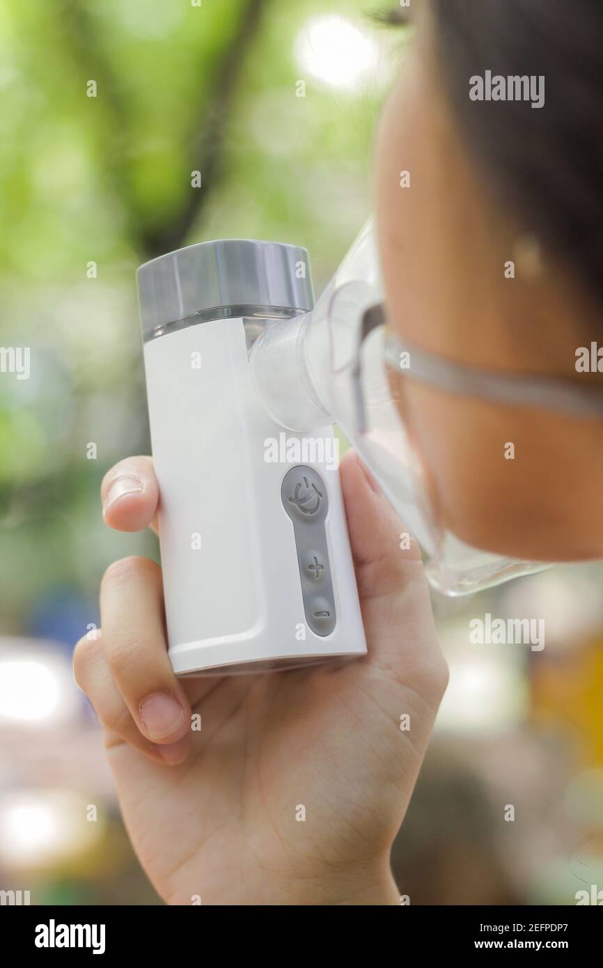 Vertical closeup shot of a female using a portable inhaler nebulizer ...