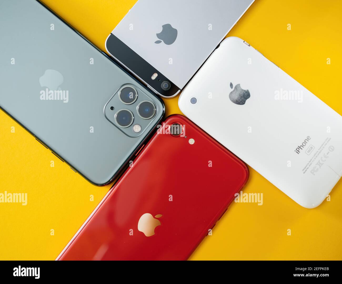PAris, France - Apr 26, 2020: View from above of four mobile Phone manufactured by Apple Computers with 3GS, Se, SE second generation and 11 Pro - isolated on yellow background Stock Photo