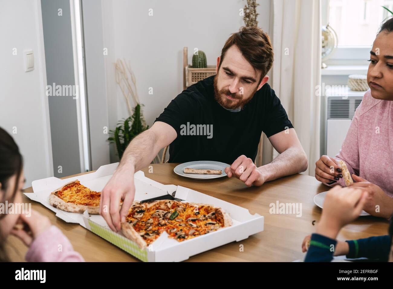 Multinational family eating vegan pizza at home Stock Photo