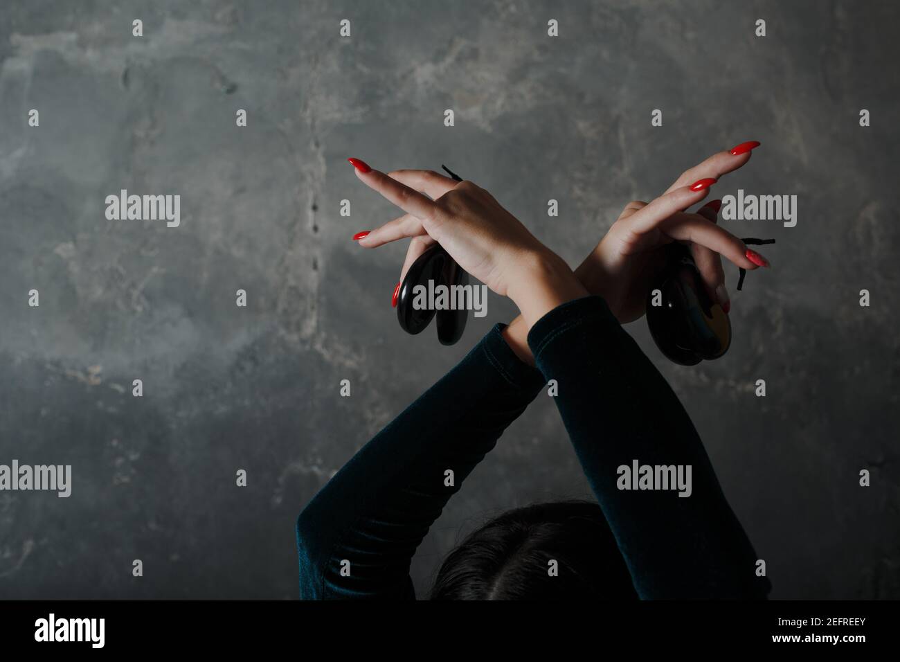 Young adult spanish woman dancing flamenco with on gray