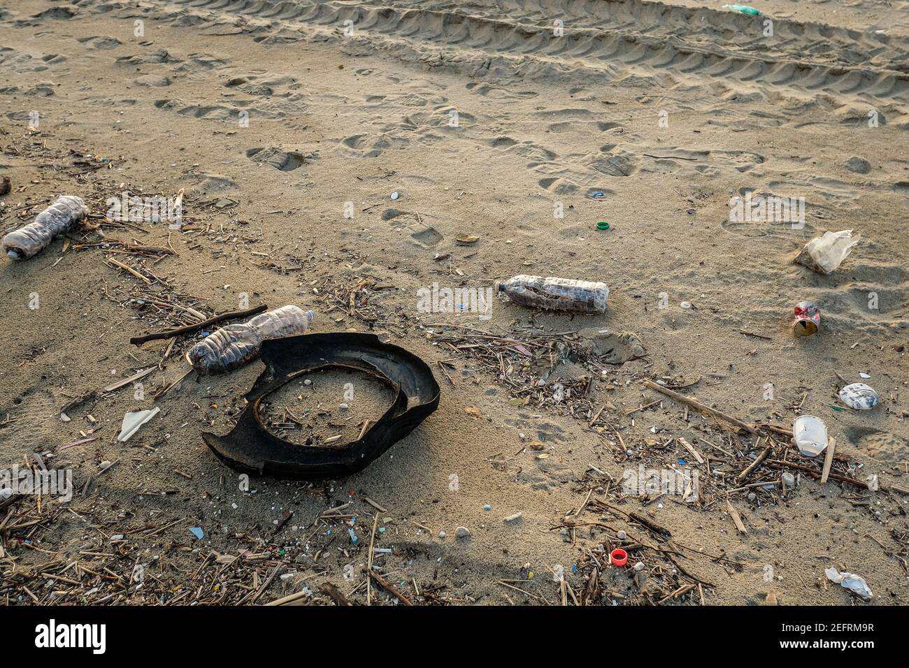 Used rubber car tyre and plastic bottles debris waste discarded on sea coast ecosystem,environmental pollution Stock Photo