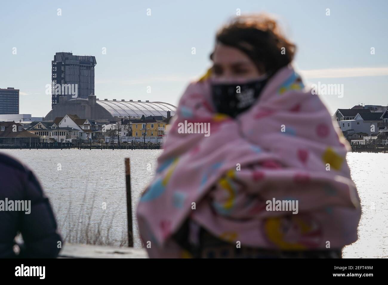Atlantic City, USA. 17th Feb, 2021. A spectator wrapped in a Disney princess blanket waits for the demolition of the former Trump Plaza Hotel and Casino in Atlantic City, USA. The hotel and casino owned by former President Donald Trump was shut down in 2014 after going bankrupt multiple times. Credit: Chase Sutton/Alamy Live News Stock Photo