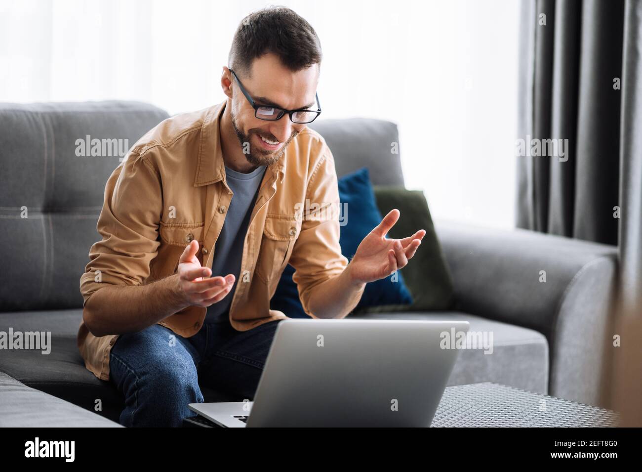 Smart male freelancer using laptop, have a video call, communicate with colleagues or friends by video conference and smiling, working from home. Remotely work concept Stock Photo
