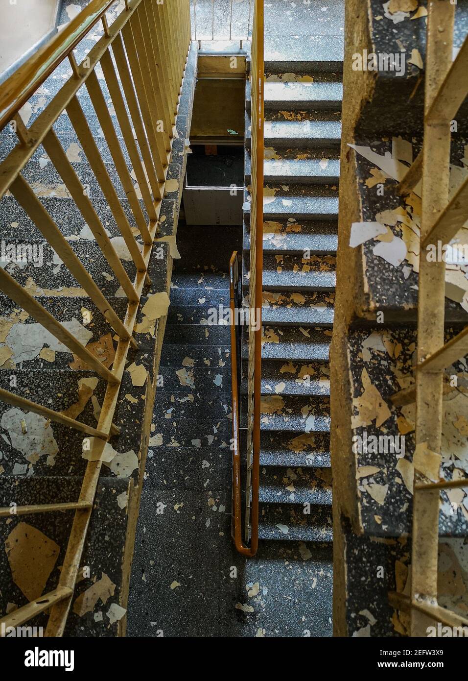 Top down view of concrete staircase with metal railings and peeled paintings from walls in old abandoned hospital Stock Photo