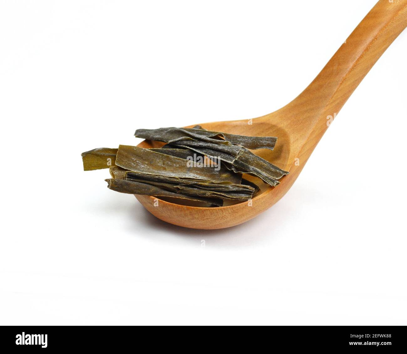 Dried kombu seaweed in a wooden spoon. Dried kombu seaweed Japanese dry kelp isolated on white