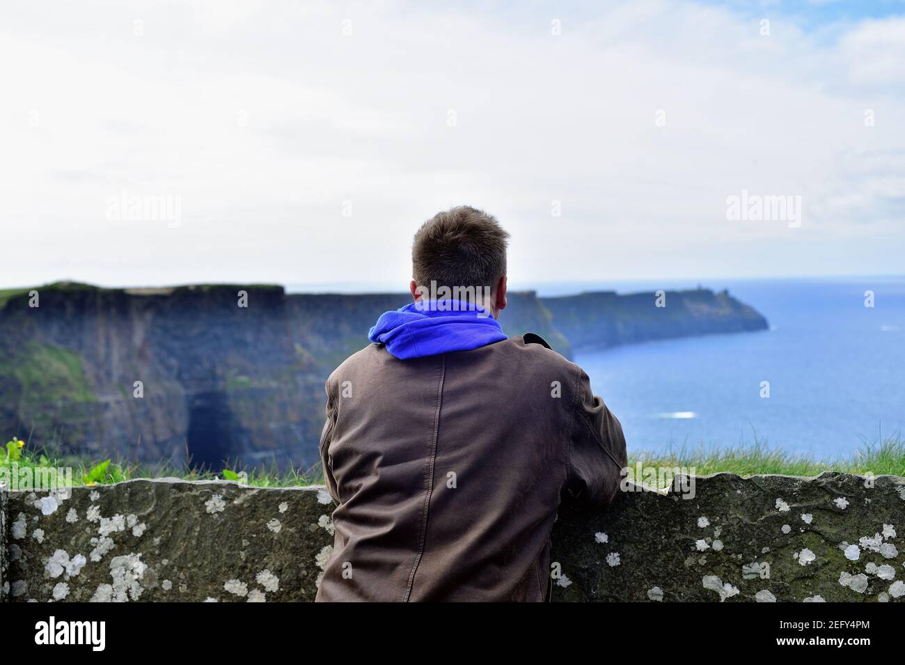 Liscannor, County Clare, Ireland. Man taking in the rugged beauty at the Cliffs of Moher. Stock Photo
