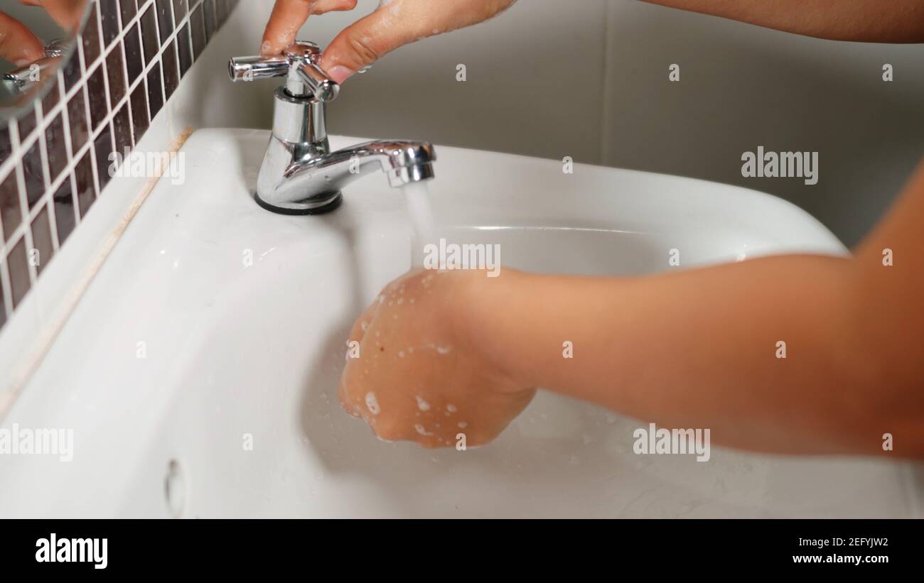 Closeup young woman hands using soap and washing hands under the water ...